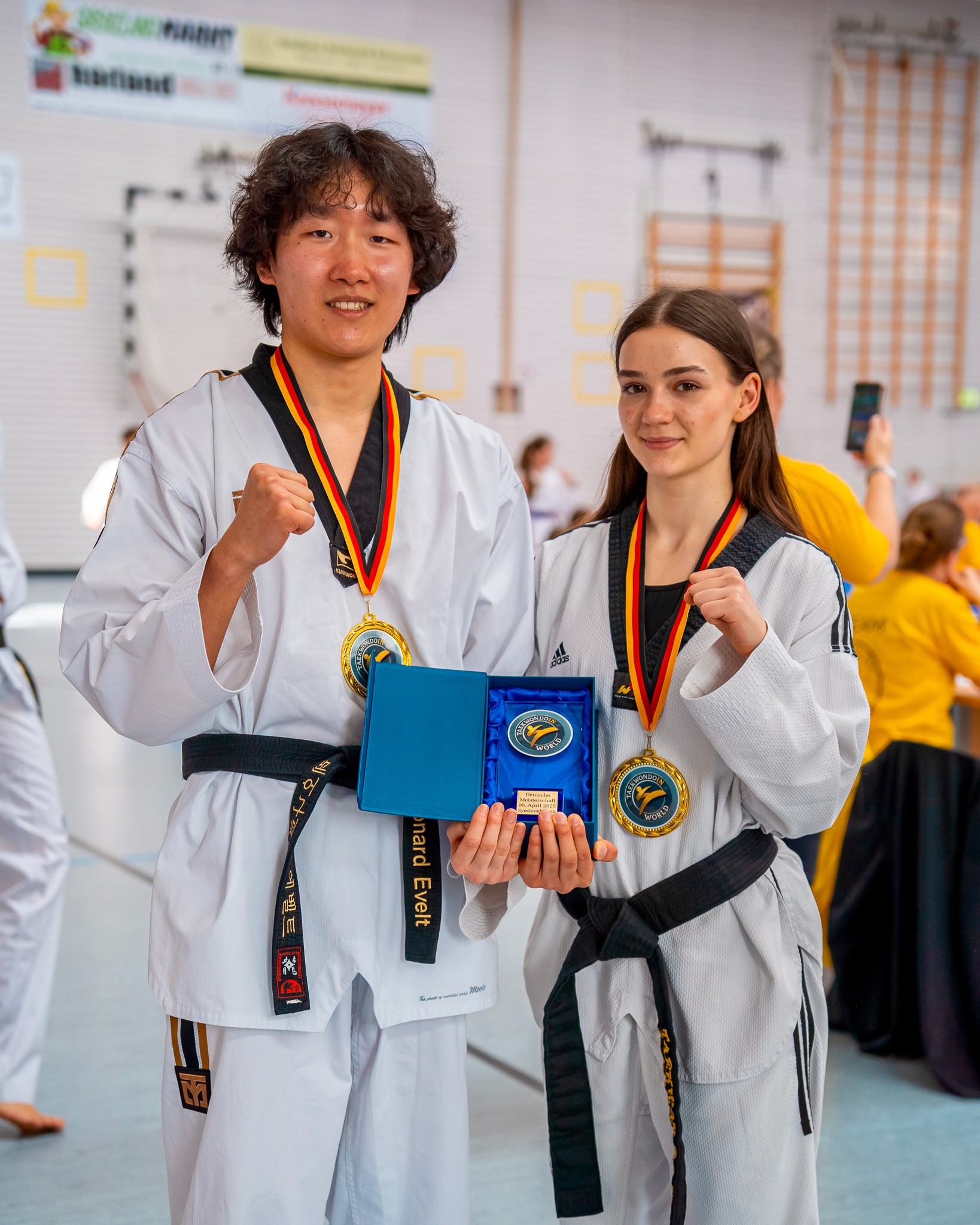 Leonard Evelt und Oleksandra Yavorshchuk, zwei Taekwondo-Trainer, halten einen Pokal in der Hand
